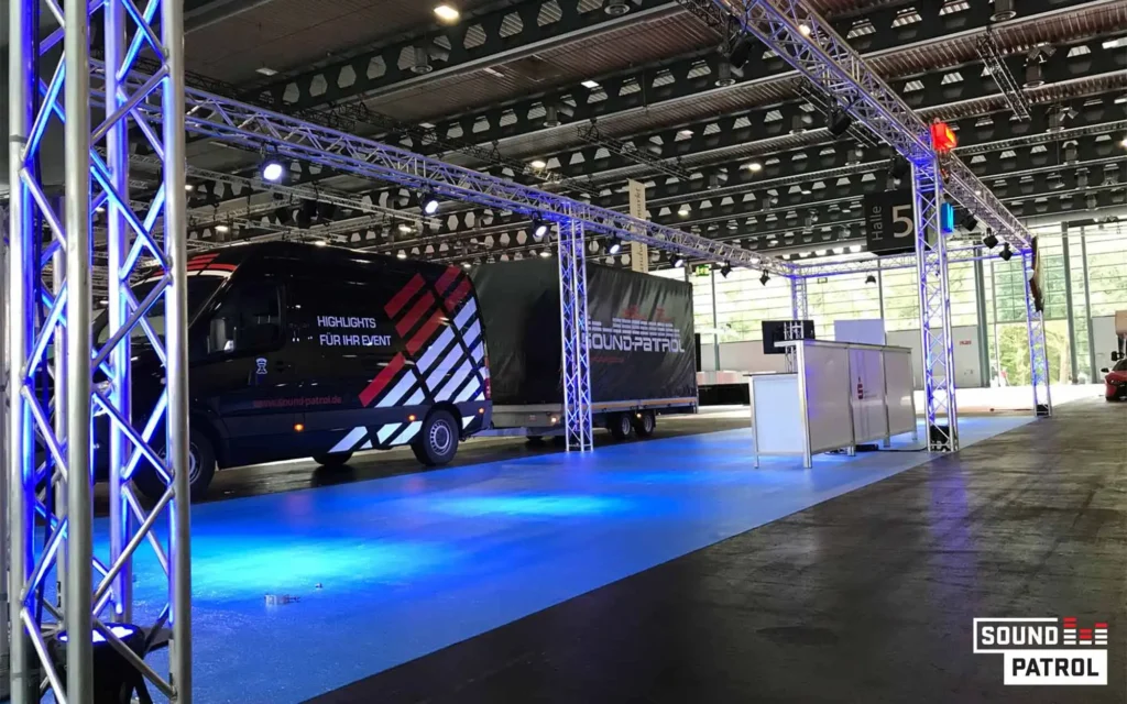 Sound Patrol Industrie und Messe: Industriehalle als Eventlocation mit langen Holztischen und Sound Patrol LED-Wand