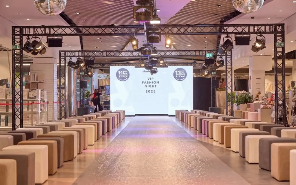 Sound Patrol Dodenhof VIP Fashion Night: Sängerin im roten Anzug auf dem Laufsteg vor großer LED-Wand mit Brooklyn-Bridge-Motiv