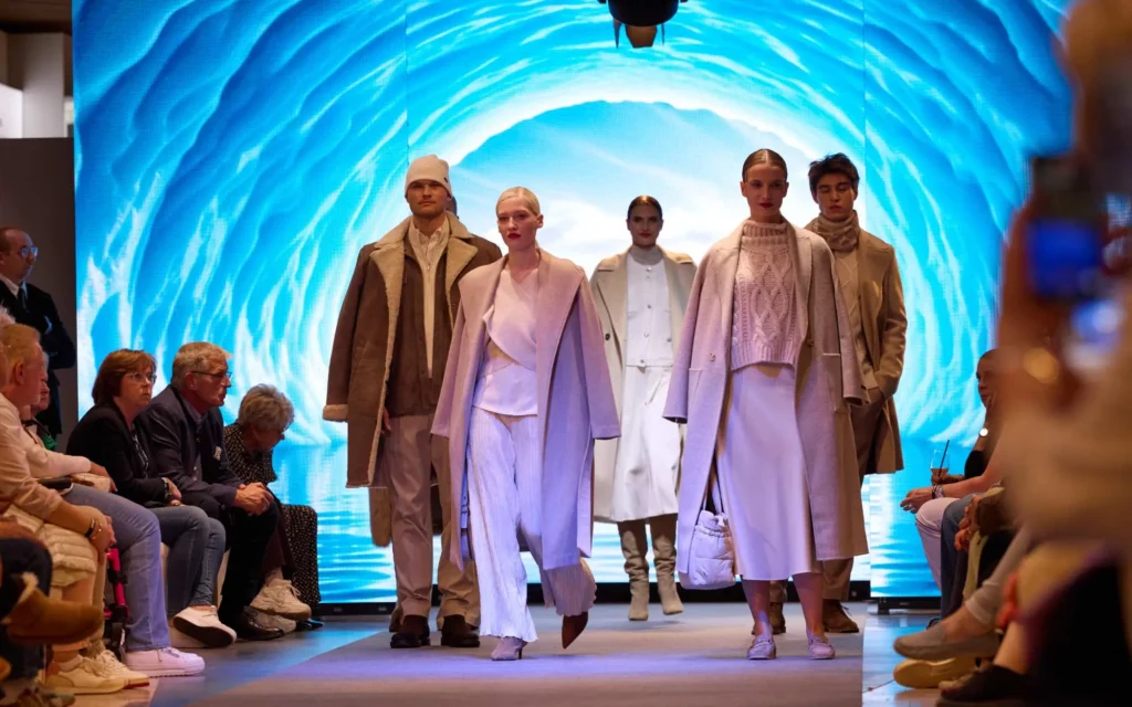 Sound Patrol Dodenhof VIP Fashion Night: Sängerin im roten Anzug auf dem Laufsteg vor großer LED-Wand mit Brooklyn-Bridge-Motiv