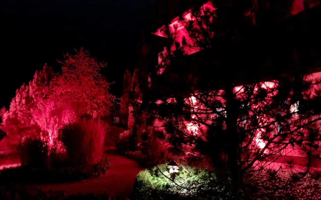 Sound Patrol Winterzauber Wachtelhof: Gartenanlage bei Nacht mit dramatischer roter LED-Illumination und festlicher Atmosphäre