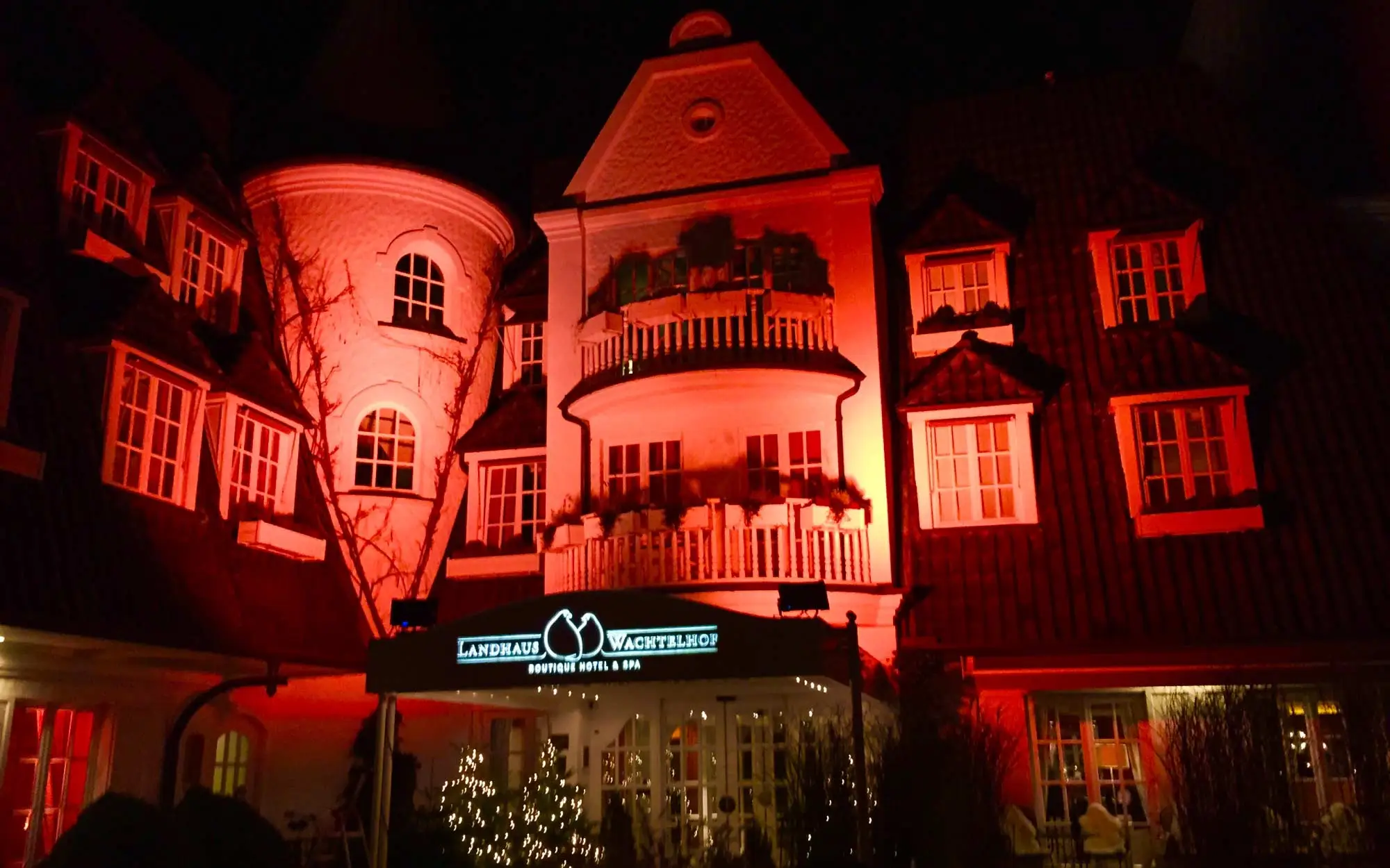 Sound Patrol Winterzauber Wachtelhof: Gartenanlage bei Nacht mit dramatischer roter LED-Illumination und festlicher Atmosphäre